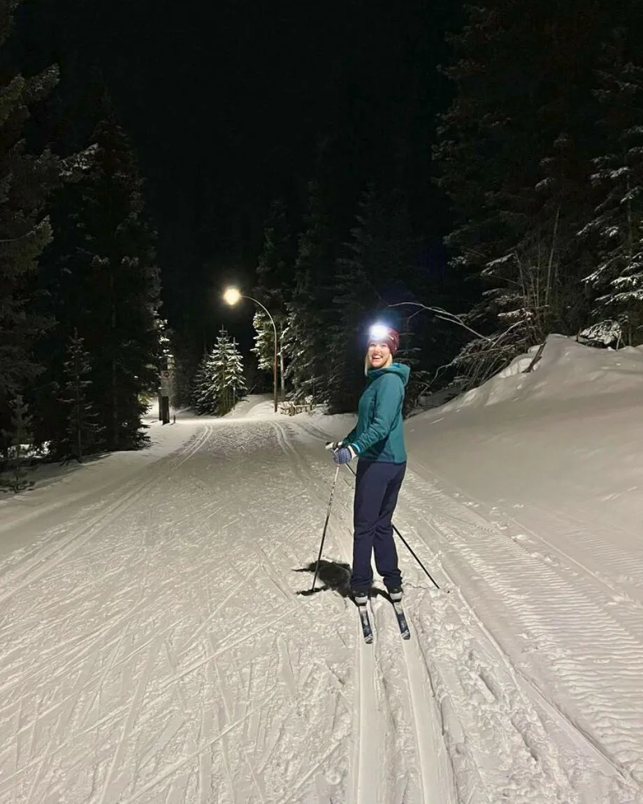 Woman with a head lamp and teal jacket night skiing at Overlander.